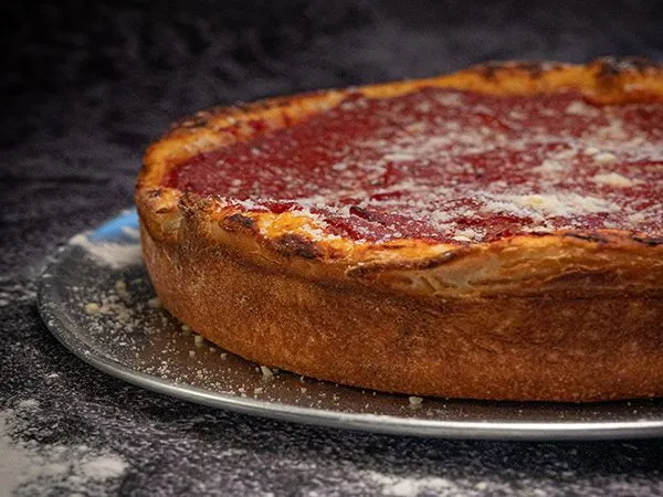 Deep dish pizza with a golden crust and tomato topping